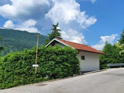a house with a bush next to a street at Peaceful Countryside Holiday Home with Terrace - One Bedroom Holiday Home with Terrace in Tolmin