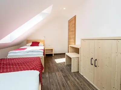 a attic bedroom with two beds and a cabinet at The Woodland Nook Apartments Bohinj - Standard Two Bedroom Apartment with Balcony in Bohinj