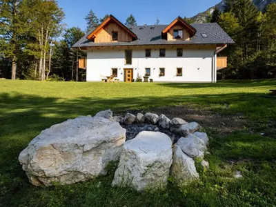 a house with a stone arch in front of a house at The Woodland Nook Apartments Bohinj - Standard Two Bedroom Apartment with Balcony in Bohinj