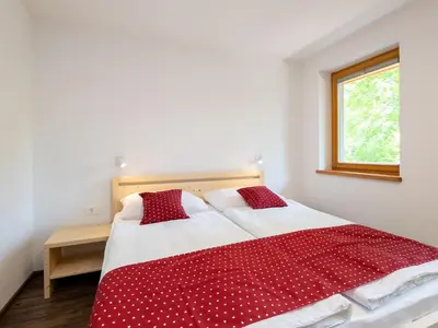 a bedroom with a red and white bed with a window at The Woodland Nook Apartments Bohinj - Standard Two Bedroom Apartment with Balcony in Bohinj
