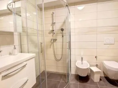 a bathroom with a shower and a toilet and a sink at Stylish Retreat with BBQ and Modern Amenities near Terme - Three Bedroom Apartment in Dobova