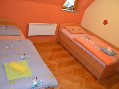 two twin beds in a room with orange walls at Two Bedroom Apartment with Balcony in Kranjska Gora