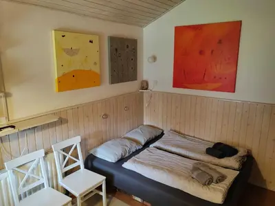 a room with a bed with two chairs and paintings at Mountain Vista Cottage with Private Sauna - One Bedroom Cottage in Škofja Loka