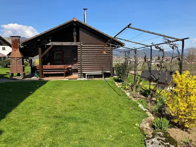 a wooden cabin with a bench in a yard at Mountain Vista Cottage with Private Sauna - One Bedroom Cottage in Škofja Loka