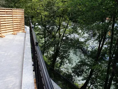 a suspension bridge in a forest with trees at Riverside Rustic Ridge Apartments with Balcony - Three Bedroom Apartment with Balcony in Slappe dʼIdria