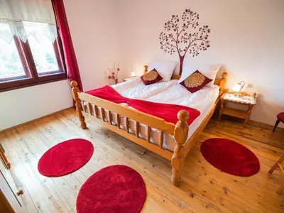 a bedroom with a wooden bed with red rugs at Bloomfield Retreat Country House with Sauna - Three Bedroom Country House in Rečica ob Savinji