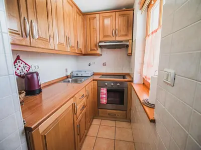 a small kitchen with wooden cabinets and a sink at Bovec Picturesque Mountain Vista Residences - Two Bedroom Apartment in Bovec