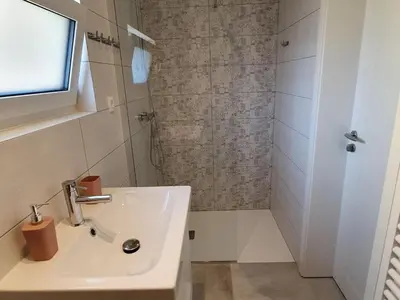 a white bathroom with a sink and a shower at Komen Getaway Holiday Home with Balcony - Four Bedroom Holiday Home with Balcony in Komen