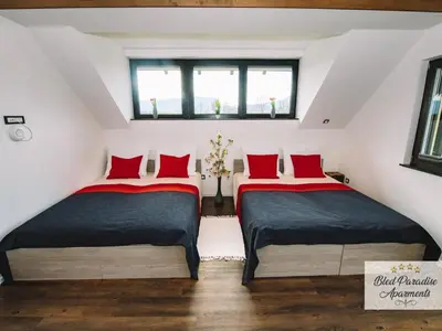 two beds in a attic room with red pillows at Bled Prestigious and Stylish Apartments - Two Bedroom Apartment with Balcony in Bled