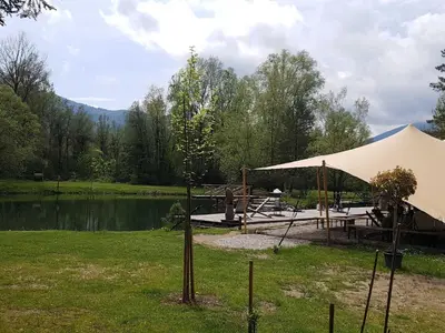 a tent with a picnic table next to a lake at Modern and Peaceful Apartment with Terrace - Two Bedroom Apartment with Terrace in Rečica ob Savinji