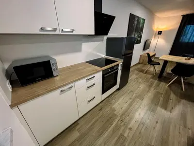 a kitchen with white cabinets and a microwave and a table at Modern and Peaceful Apartment with Terrace - Two Bedroom Apartment with Terrace in Rečica ob Savinji