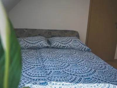 a bed with a blue and white comforter and two pillows at Comfortable Apartment with Mountain View - One Bedroom Apartment in Bovec