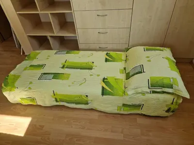 a bed with green and yellow sheets and pillows at Comfortable Apartment with Mountain View - One Bedroom Apartment in Bovec