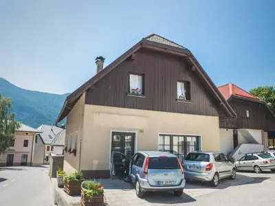 a building with cars parked in a parking lot at Comfortable Apartment with Mountain View - One Bedroom Apartment in Bovec