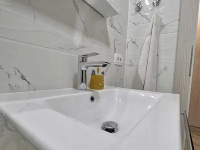 a white sink with a faucet in a bathroom at Cozy and Chic Apartment in Kranjska Gora - Studio Apartment in Kranjska Gora