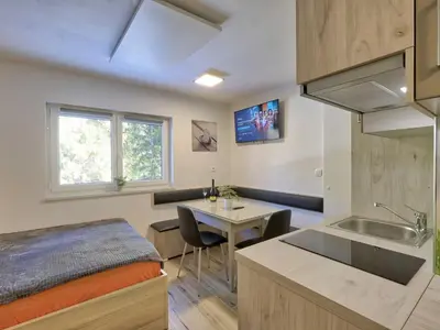 a room with a bed and a kitchen with a table at Cozy and Chic Apartment in Kranjska Gora - Studio Apartment in Kranjska Gora