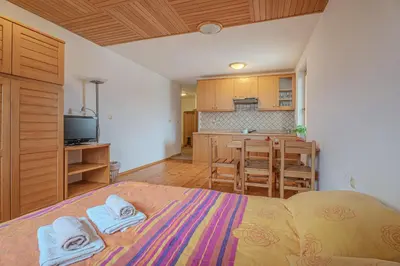 a bedroom with a bed with towels on it and a kitchen at Oblak Estate Apartments in Ortnek