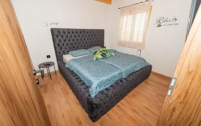 a bedroom with a large bed with a black headboard at RANČ Dida