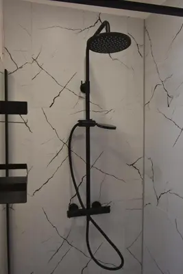 a shower in a bathroom with marble walls at Apartma Fontana in Ljubljana