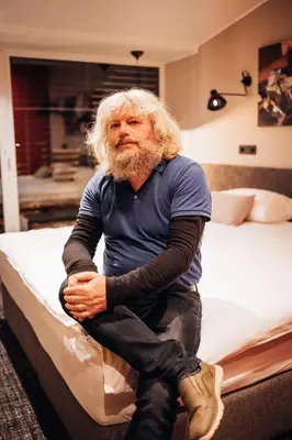 a man sitting on top of a bed at Hotel Kunst in Krško