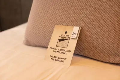 a tag on the side of a laptop on a bed at Hotel Kunst in Krško