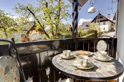 a table on a balcony with tea cups and a pizza at Lake Bled Holiday Home in Bled