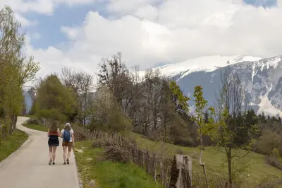 two women walking down a road with mountains in the background at Lake Bled Holiday Home in Bled