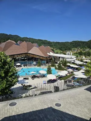 a resort with a pool with umbrellas and tables at Apartman O Terme Olimia in Ravne na Koroškem
