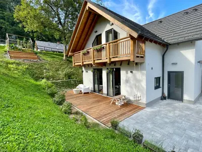 a house with a wooden deck next to a yard at Alpennelke family apartment in Bohinjska Bela