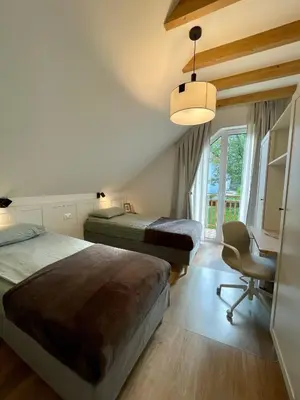 a bedroom with two beds and a desk and a chair at Alpennelke family apartment in Bohinjska Bela