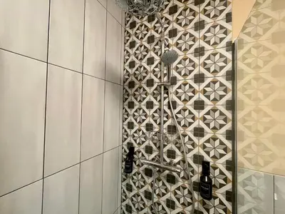 a shower in a bathroom with a tile wall at Alpennelke family apartment in Bohinjska Bela
