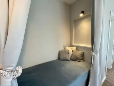 a small bed in a room with a curtain at Alpennelke family apartment in Bohinjska Bela