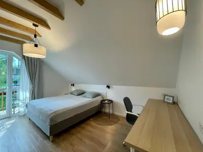 a bedroom with a bed and a wooden table at Alpennelke family apartment in Bohinjska Bela