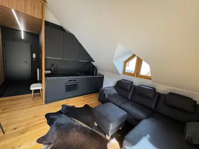 a living room with a black couch and a kitchen at Apartment Kranjska Gora Diamond in Kranjska Gora
