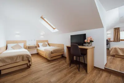 a hotel room with two beds and a desk with a television at Gostišče Iršič in Slovenska Bistrica