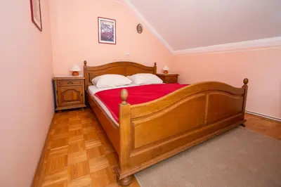 a bedroom with a wooden bed with a red blanket at Winery Toplak in Juršinci