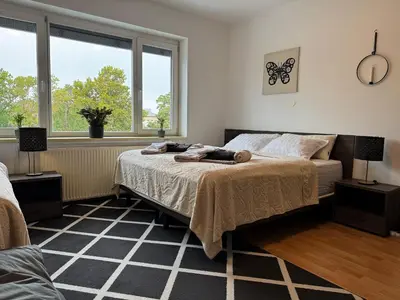 a bedroom with a bed and two windows at RailwayRooms22 in Ljubljana