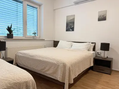 two beds in a white room with two windows at RailwayRooms22 in Ljubljana