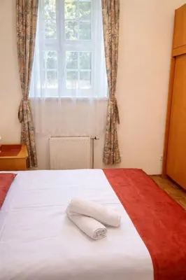 a white towel laying on a bed with a window at Ana Marija Apartment - Vila Golf in Rogaška Slatina