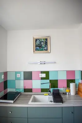 a kitchen with a sink and a colorful tile wall at Apartment River Ljubljanica in Ljubljana