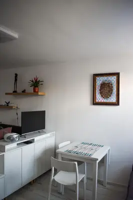 a white dining room with a table and a tv at Apartment River Ljubljanica in Ljubljana