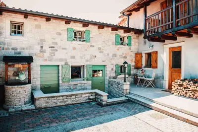 a stone building with green doors and a patio at Lavandula House in Štanjel