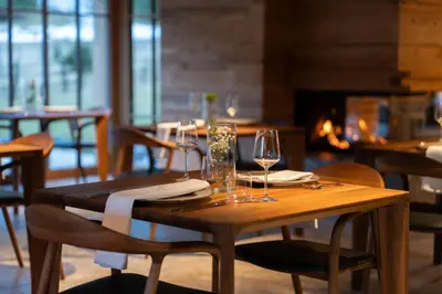 a wooden table with wine glasses and a fireplace at Jakobs Lodge in Zgornje Gorje
