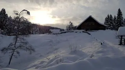 a field covered in snow with a barn in the background at planinski dom Goška Ravan in Kamna Gorica
