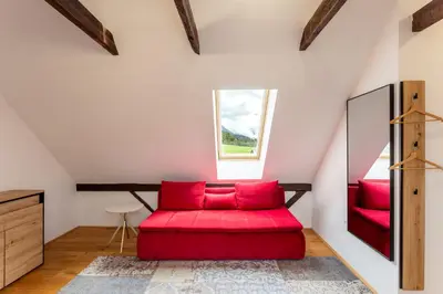 a red couch in a room with a window at Pod Gora Boutique Hotel in Kranjska Gora