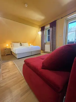 a bedroom with a bed and a red couch at Pod Gora Boutique Hotel in Kranjska Gora