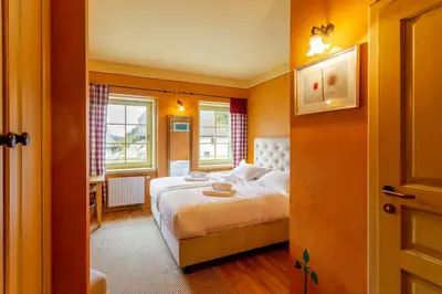 a bedroom with a bed and two windows at Pod Gora Boutique Hotel in Kranjska Gora
