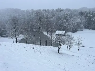 a snow covered hill with trees and a house at Prista Ranch Cirkulane in Rove