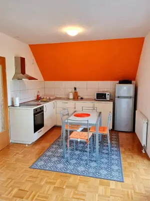 a kitchen with a table and chairs and an orange wall at Apartment Veduta in Bovec