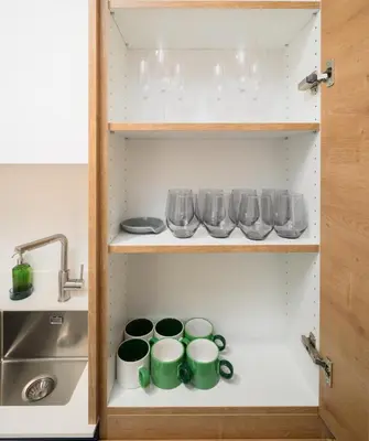 a cupboard with mugs and glasses and a sink at Petka apartments in Ljubljana